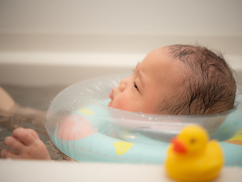 バスタブで浮き輪を使う子どもの写真